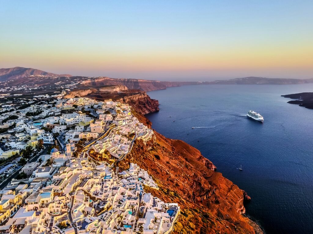 pexels-photo-1518498-1518498 Stunning aerial shot of Santorini coast at sunset with a cruise ship in the Aegean Sea.
