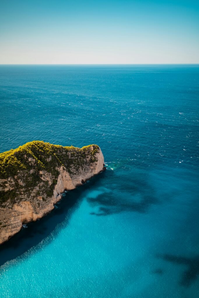 pexels-photo-18380194-18380194 Stunning aerial shot of Zakynthos coastline, featuring turquoise waters and rugged cliffs on a sunny day.